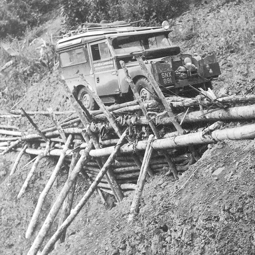 A LandRover drives over a bridge made of tree trunks - Oxcam Expedition far east 1955
